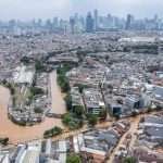 Foto udara luapan Sungai Ciliwung saat banjir Jakarta Maret 2025, menggenangi permukiman dan infrastruktur di sekitarnya.